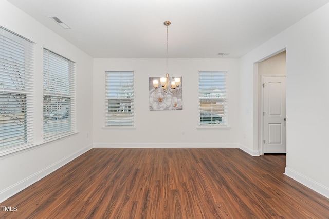 unfurnished dining area with an inviting chandelier and dark hardwood / wood-style flooring