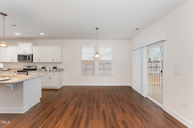 kitchen with white cabinetry, hanging light fixtures, a breakfast bar area, and stainless steel appliances