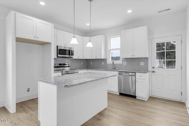 kitchen with hanging light fixtures, white cabinetry, appliances with stainless steel finishes, and a kitchen island