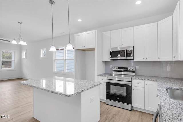 kitchen with tasteful backsplash, hanging light fixtures, stainless steel appliances, light hardwood / wood-style floors, and white cabinets