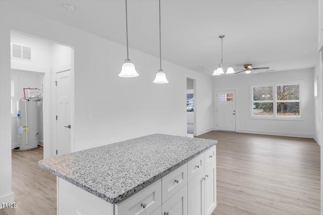 kitchen with light hardwood / wood-style flooring, water heater, light stone countertops, white cabinets, and decorative light fixtures