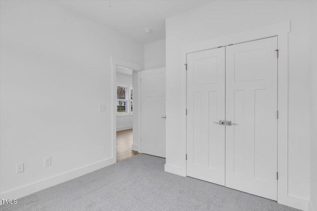 unfurnished bedroom featuring light colored carpet and a closet