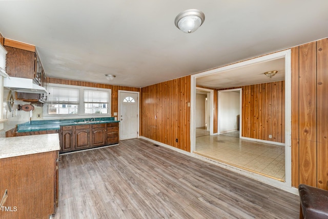 kitchen featuring wood-type flooring, wooden walls, and sink