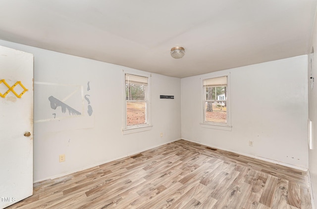 spare room with a wealth of natural light and light wood-type flooring