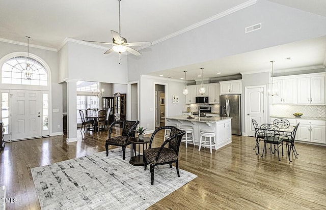 entrance foyer with hardwood / wood-style floors, a towering ceiling, ornamental molding, and ornate columns