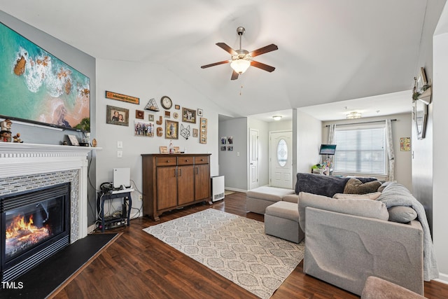 living room featuring dark hardwood / wood-style flooring, vaulted ceiling, a tile fireplace, and ceiling fan