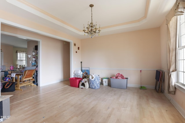 playroom featuring plenty of natural light, light hardwood / wood-style flooring, a chandelier, and a tray ceiling