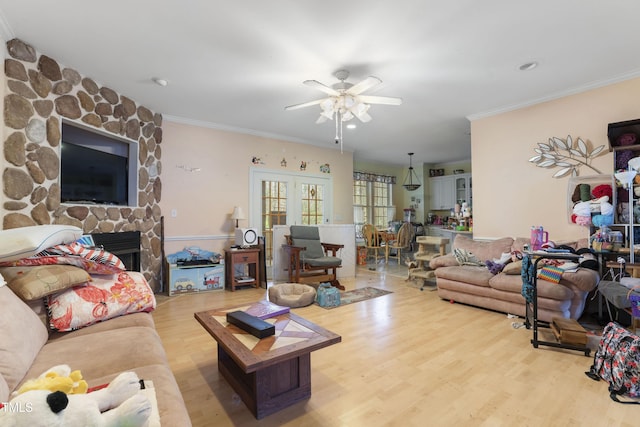 living room with ornamental molding, light wood-type flooring, ceiling fan, and a fireplace