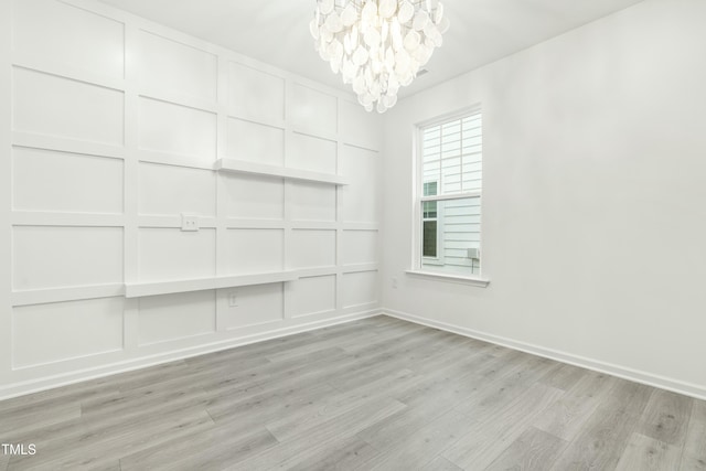 unfurnished room featuring a notable chandelier and light hardwood / wood-style floors