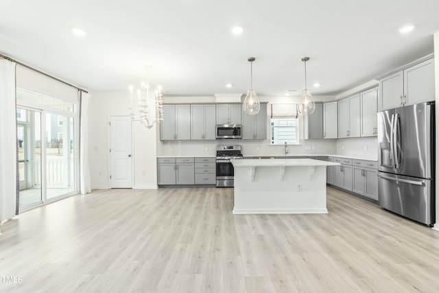 kitchen featuring gray cabinetry, hanging light fixtures, stainless steel appliances, and a center island