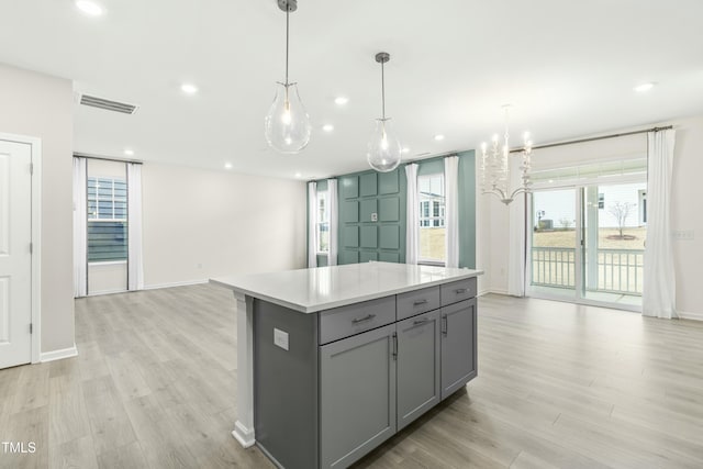 kitchen with decorative light fixtures, gray cabinets, light hardwood / wood-style floors, and a kitchen island