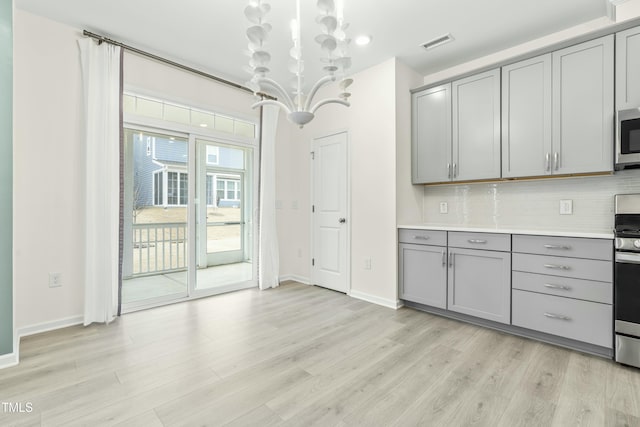 kitchen featuring backsplash, stainless steel appliances, light wood-type flooring, and gray cabinetry