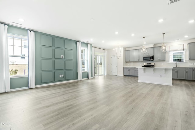 unfurnished living room with sink and light hardwood / wood-style flooring