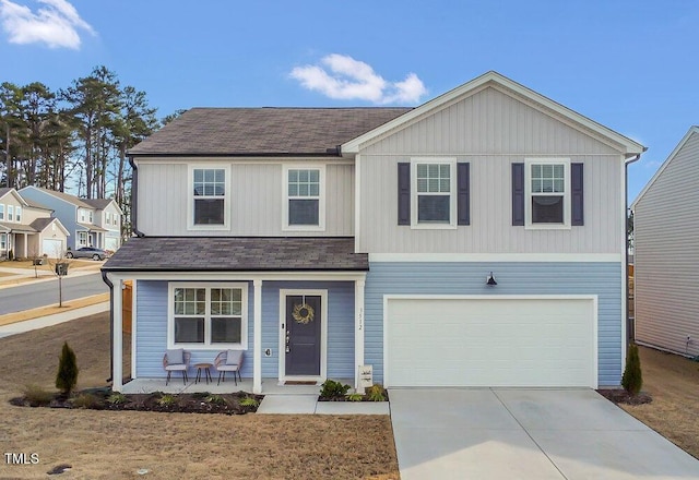 traditional home featuring a porch, an attached garage, concrete driveway, and roof with shingles