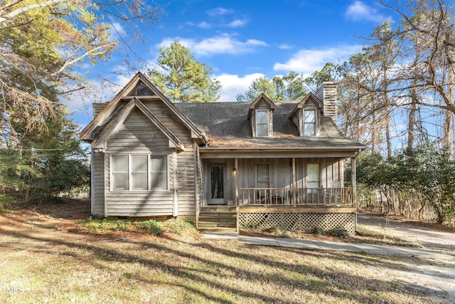 cape cod home featuring a front lawn and covered porch