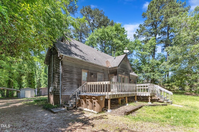 view of front of house with an outdoor structure, a deck, roof with shingles, a storage unit, and stairway