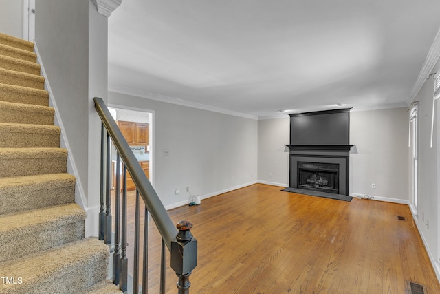 unfurnished living room featuring crown molding, a fireplace, wood finished floors, stairway, and baseboards