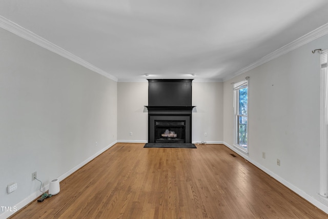 unfurnished living room featuring baseboards, ornamental molding, a fireplace, and wood finished floors
