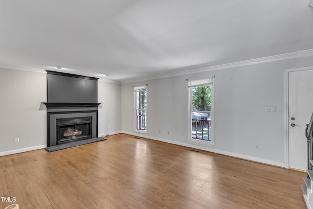 unfurnished living room featuring a fireplace, baseboards, wood finished floors, visible vents, and ornamental molding