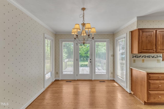 doorway to outside with crown molding, light wood-type flooring, wallpapered walls, and a notable chandelier