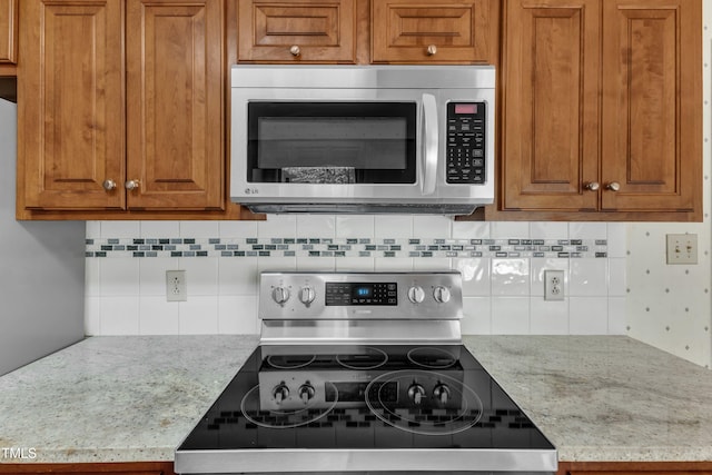 kitchen with brown cabinets, stainless steel appliances, and tasteful backsplash