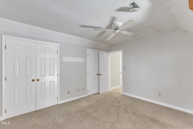 unfurnished bedroom with visible vents, multiple closets, light carpet, attic access, and vaulted ceiling
