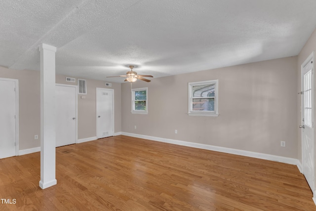 unfurnished living room with a ceiling fan, light wood finished floors, a textured ceiling, and visible vents