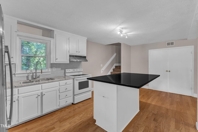 kitchen featuring a sink, white range with electric cooktop, a textured ceiling, under cabinet range hood, and visible vents
