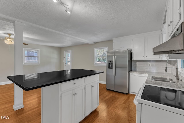 kitchen with white appliances, white cabinetry, a textured ceiling, and a kitchen island