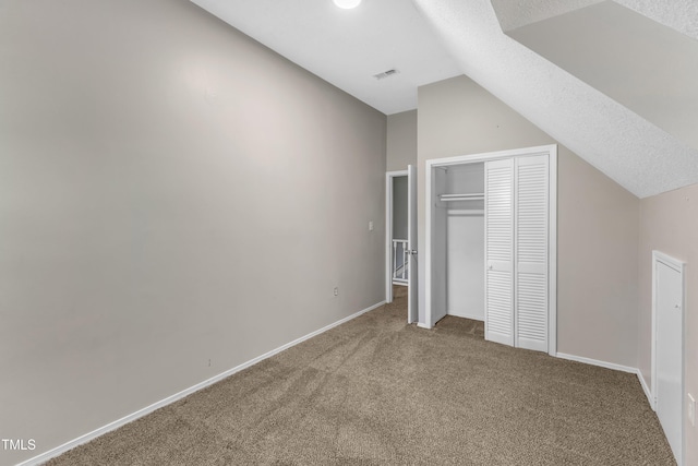 unfurnished bedroom featuring baseboards, carpet, a closet, and lofted ceiling
