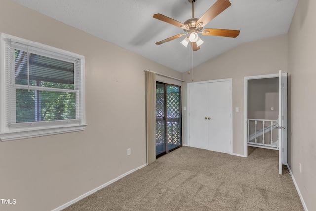 unfurnished bedroom featuring baseboards, carpet flooring, vaulted ceiling, and multiple windows