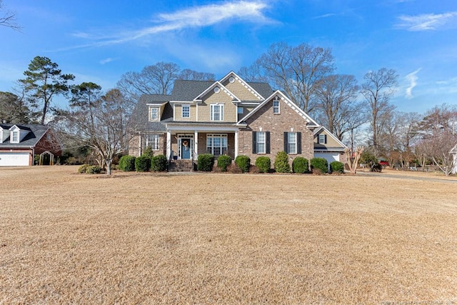 craftsman-style home featuring a garage, covered porch, and a front yard