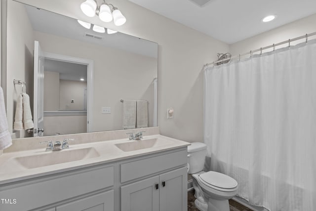 bathroom with toilet, double vanity, a sink, and visible vents