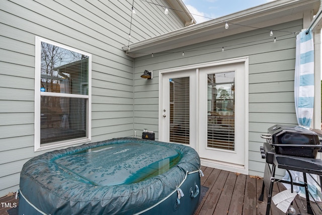 wooden terrace with a hot tub and area for grilling