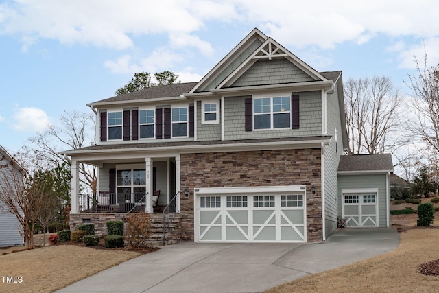 craftsman house with an attached garage, stone siding, a porch, and concrete driveway