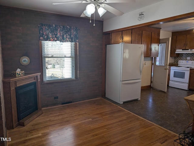 kitchen featuring dark hardwood / wood-style flooring, white appliances, ceiling fan, and brick wall