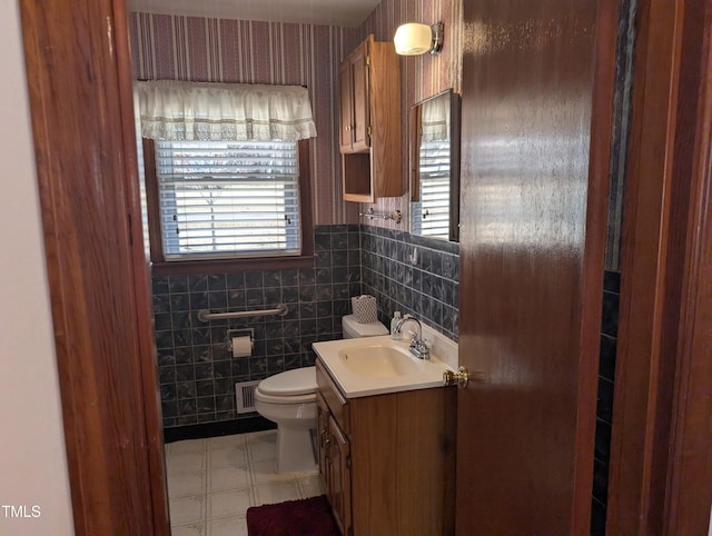 bathroom with vanity, tile walls, and toilet