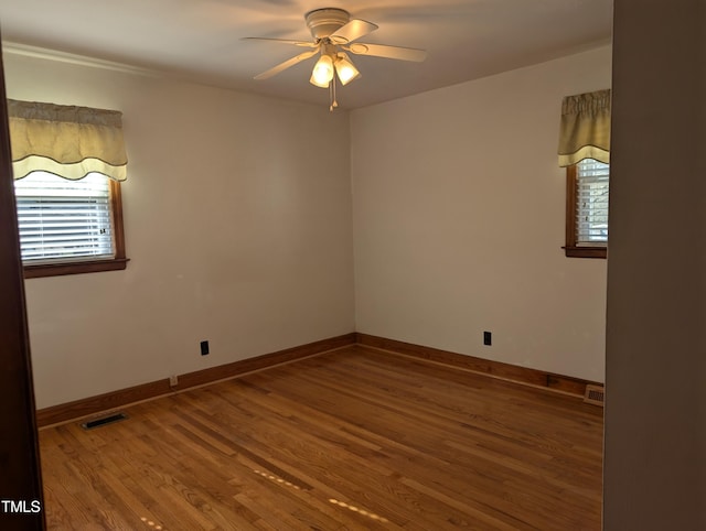 unfurnished room featuring a healthy amount of sunlight, hardwood / wood-style floors, and ceiling fan