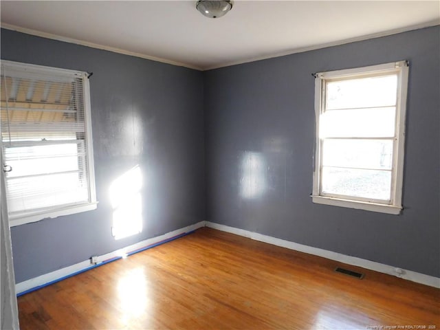 spare room with crown molding, wood-type flooring, and a healthy amount of sunlight