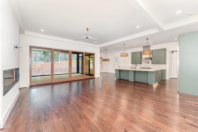 unfurnished living room featuring ceiling fan and dark hardwood / wood-style flooring