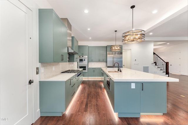 kitchen featuring stainless steel appliances, dark hardwood / wood-style flooring, a large island with sink, sink, and pendant lighting