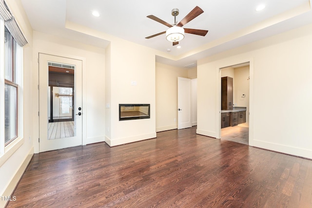 unfurnished living room featuring dark hardwood / wood-style flooring and ceiling fan