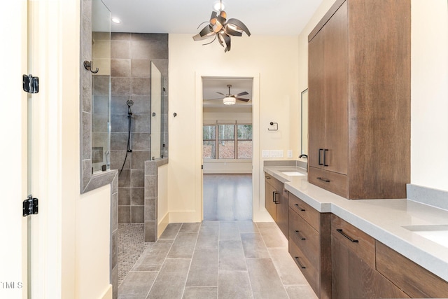 bathroom featuring tile patterned floors, ceiling fan with notable chandelier, vanity, and tiled shower