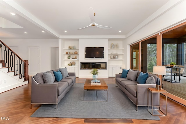 living room with ceiling fan, built in shelves, and hardwood / wood-style floors