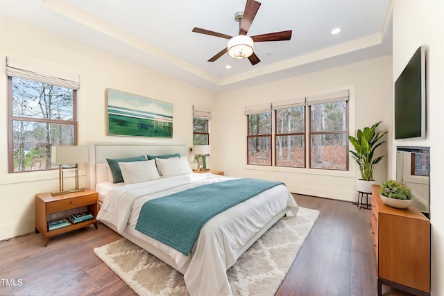 bedroom featuring a tray ceiling, dark wood-type flooring, and ceiling fan