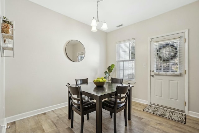 dining room with light hardwood / wood-style floors and a notable chandelier