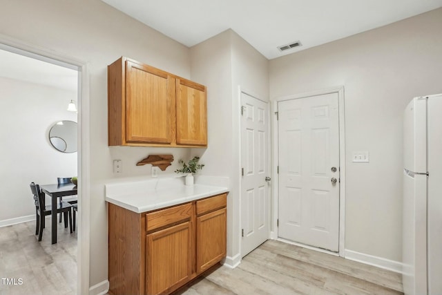 kitchen with white refrigerator and light hardwood / wood-style flooring