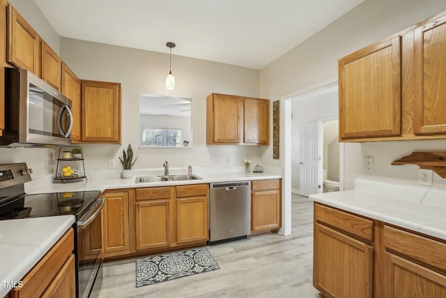 kitchen with appliances with stainless steel finishes, sink, hanging light fixtures, and light wood-type flooring