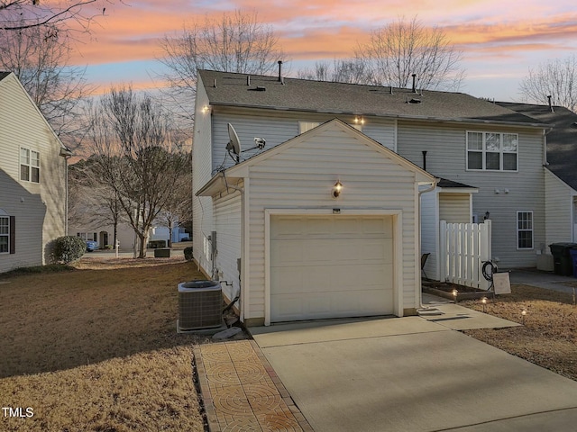 view of front of house with a garage, a yard, and central AC unit