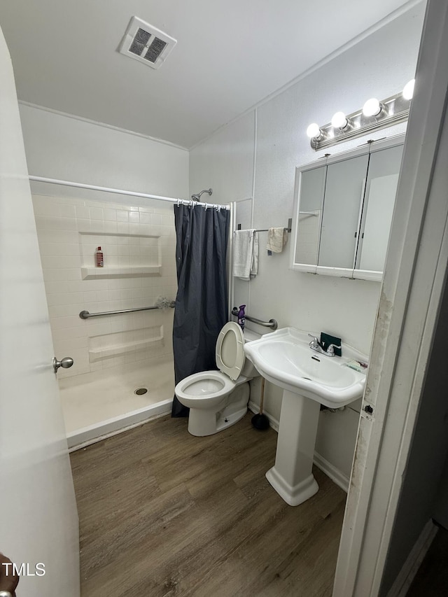 bathroom with hardwood / wood-style floors, a shower with curtain, and toilet